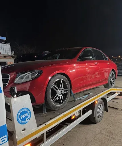 Noćno šlepanje crvene limuzine na platformi šlep vozila
